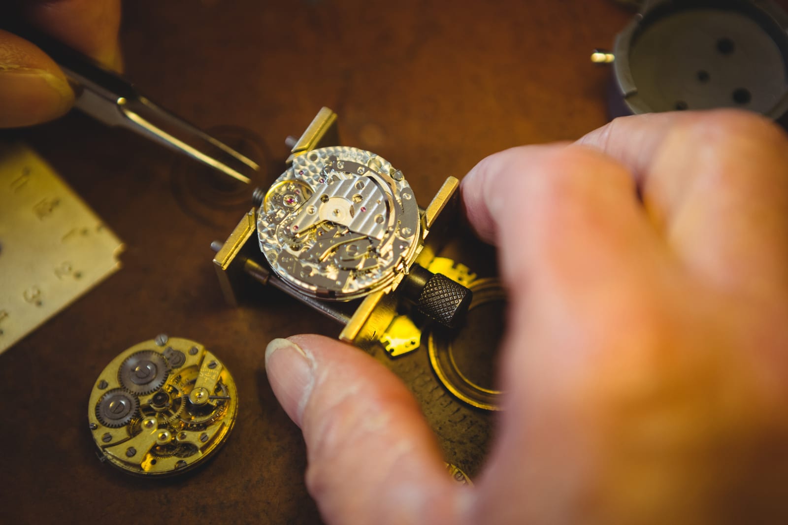 Mani al lavoro su un movimento durante la manutenzione di un orologio al quarzo