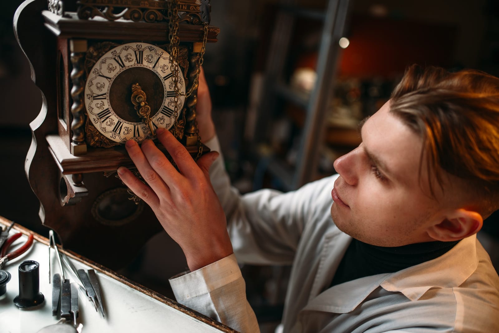 Orologiaio regola le lancette di un orologio meccanico antico
